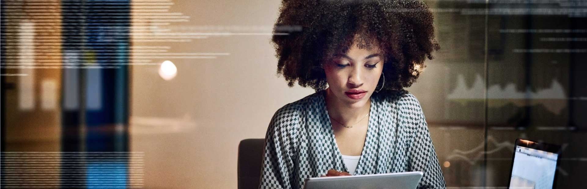 Woman taking notes indoors with laptop screen open